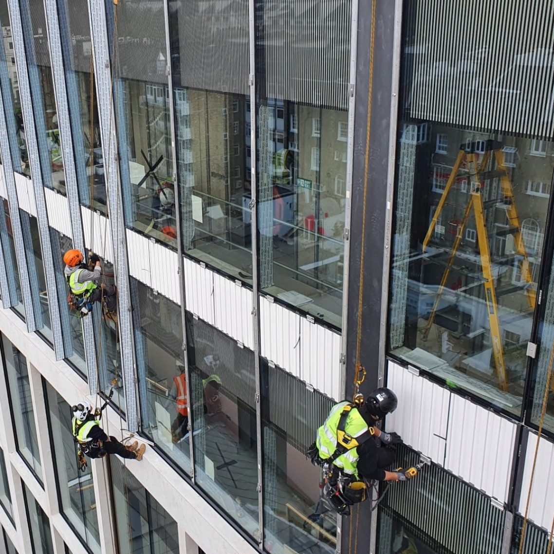 London rope access IRATA qualified workers cleaning windows on a high-rise building in the city of London.